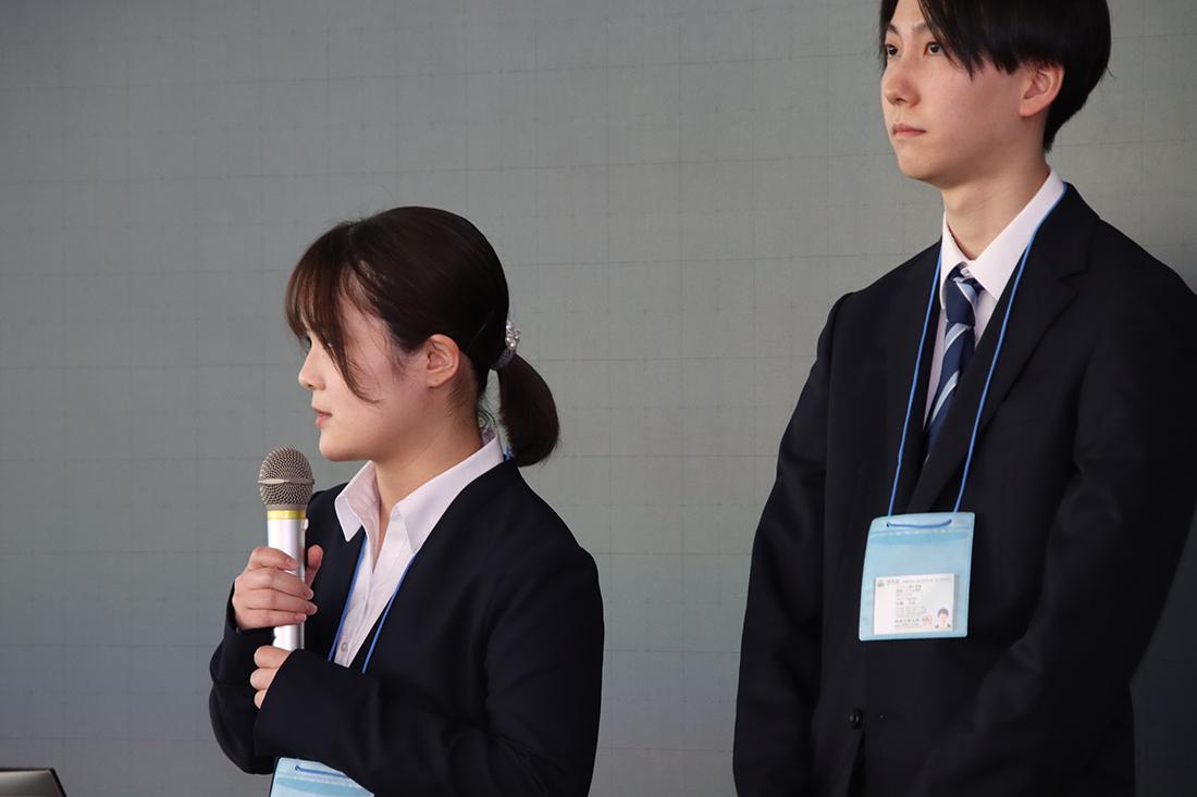 黒板の前で話すスーツ姿の二人