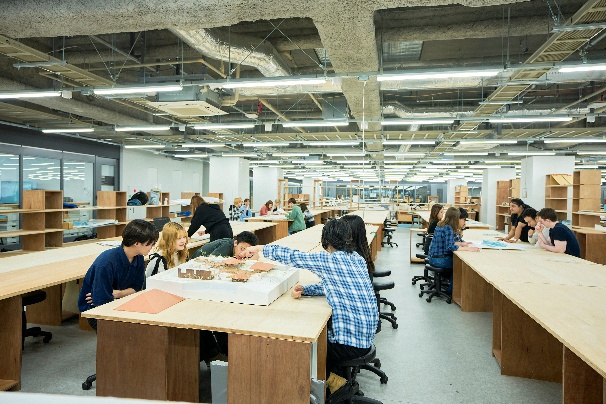 長い作業台が並ぶオープンな学習室で、複数人が作業している  